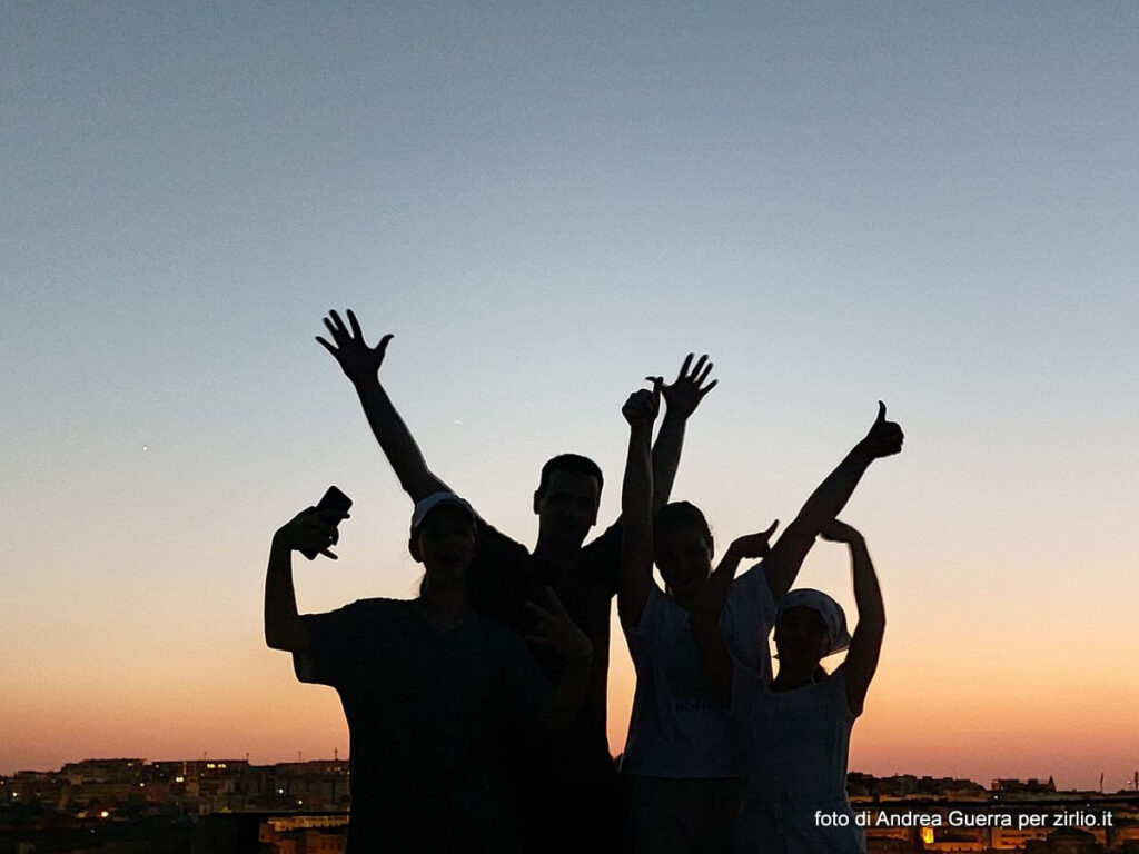 Una famiglia di escursionisti è felice per aver completato il tour fino al belvedere di Murgia Timone al tramonto. Il loro selfie li mostra come silouette piene di energia con il tramonto alle spalle e Matera in lontananza.